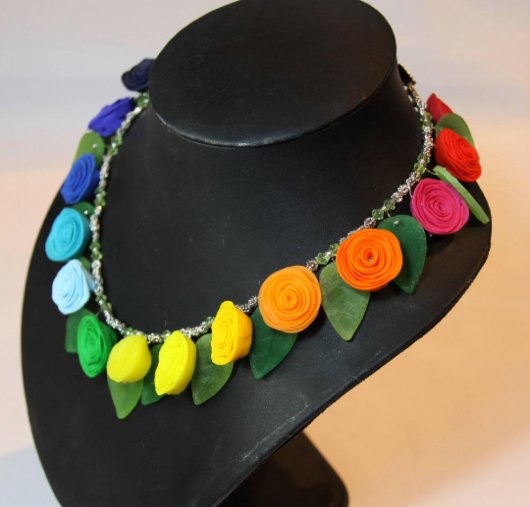 Collier arc en ciel composé de fleurs roses multicolores en pate polymère et de feuilles vertes en verre sur un rang de perles argentées